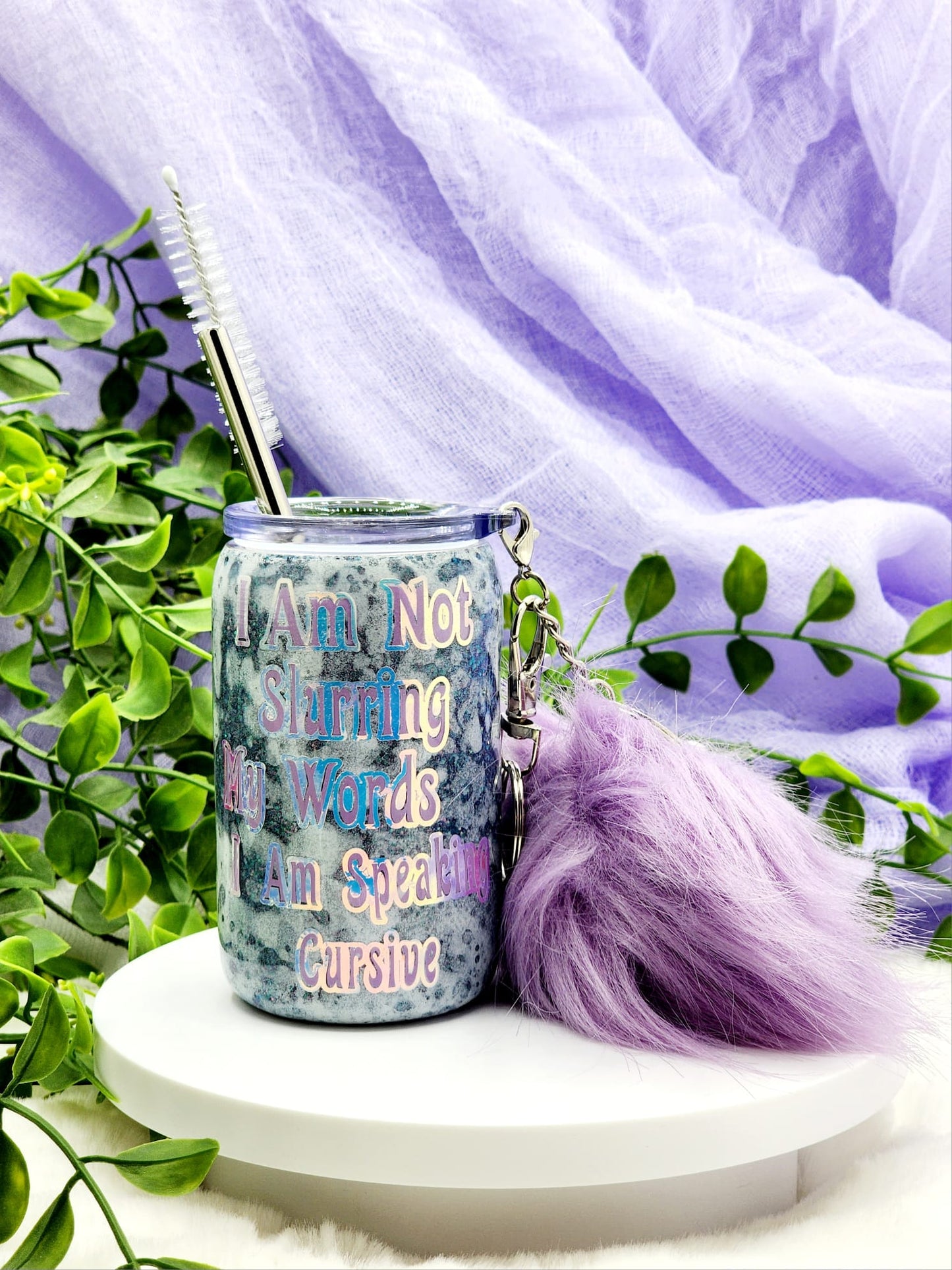 A stainless steel shot glass with a clear sliding lid and a stainless steel straw, inscribed with a humorous quote, accompanied by a purple furry key ring and a white bubble surface by Tumbler Funatics.