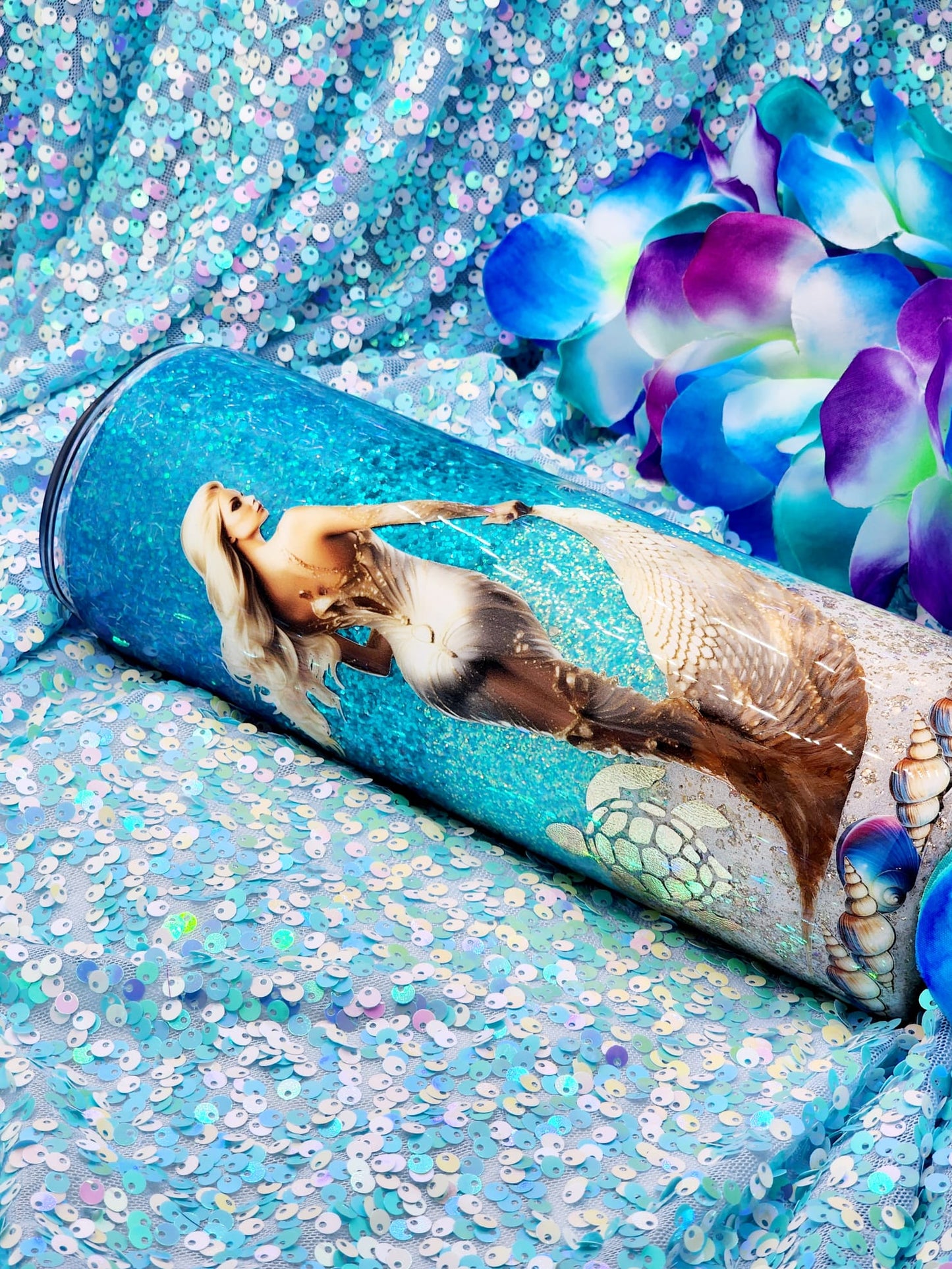 A tumbler with a mermaid and beach-themed design, featuring palm trees, seashells, and a quote 'You are loved now and forever' by Tumbler Funatics